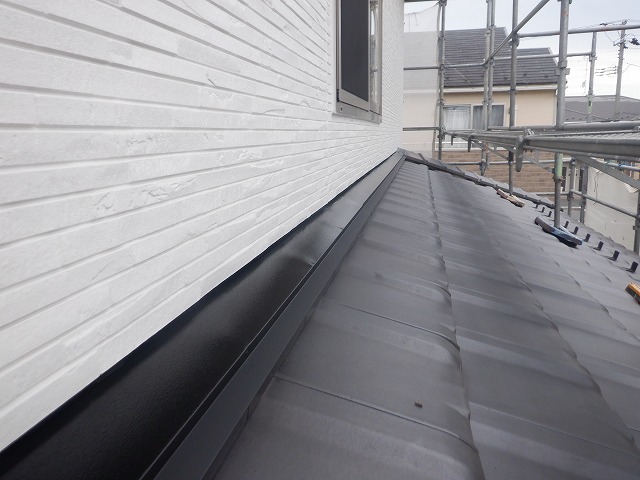 雨押え板金に上塗り1回目を塗装している様子