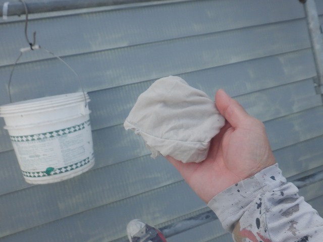 水研ぎ後のトタン屋根に汚れが残っていないか確認している様子