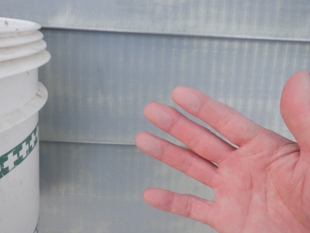 トタン屋根の表面を指でなぞって汚れを確認した様子
